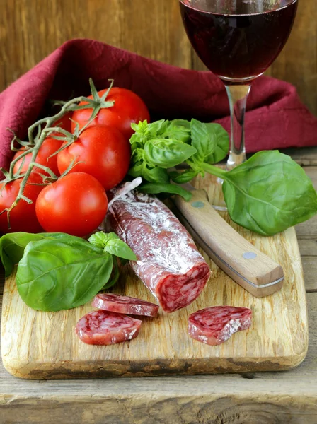 Bodegón de delicadeza salami, tomates y albahaca - estilo rústico — Foto de Stock