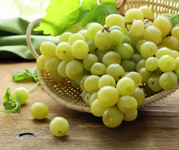 Białych winogron w kosz na drewnianym stole — Zdjęcie stockowe