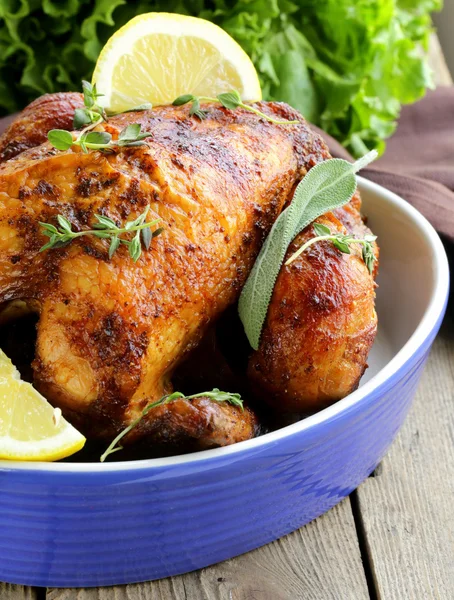 Roasted chicken with herbs served on a plate with lemon — Stock Photo, Image