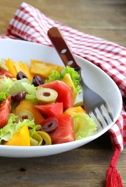 Salat mit bunten Tomaten und Oliven auf dem Holztisch — Stockfoto