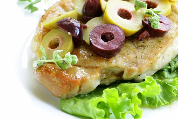 Pork steak with green and black olives for garnish — Stock Photo, Image