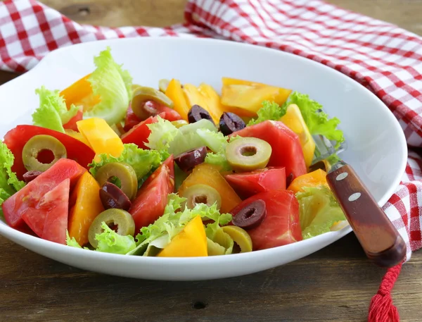 Salada de tomates coloridos e azeitonas na mesa de madeira — Fotografia de Stock