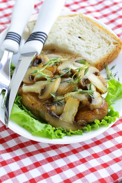 Steak de porc avec sauce aux champignons sur une assiette blanche — Photo