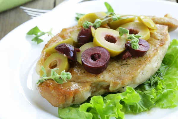 Pork steak with green and black olives for garnish — Stock Photo, Image