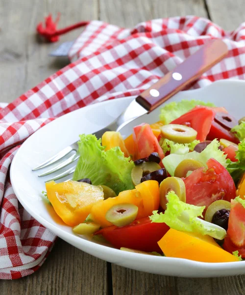 Salad of colorful tomatoes and olives on the wooden table — Stock Photo, Image