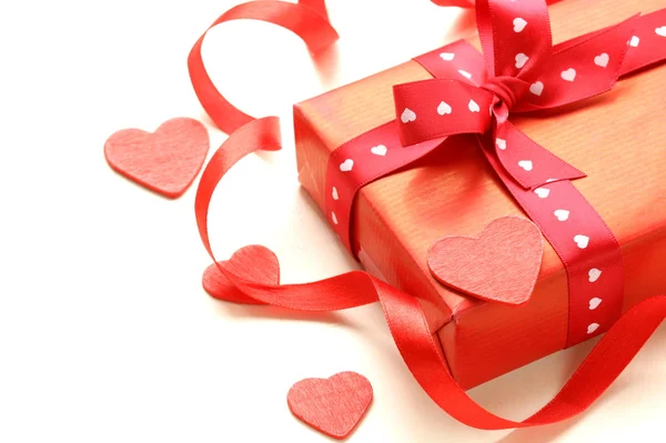 Şerit ve kalpleri beyaz zemin üzerine kırmızı hediye kutusu — Stok fotoğraf