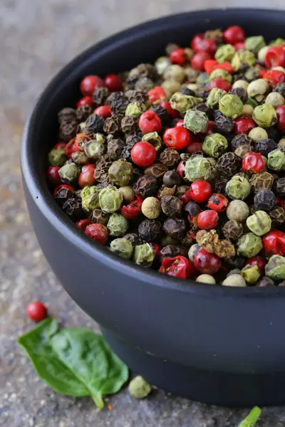 Verschiedene rote, schwarze und grüne Paprika in einer Schüssel auf dem Tisch — Stockfoto