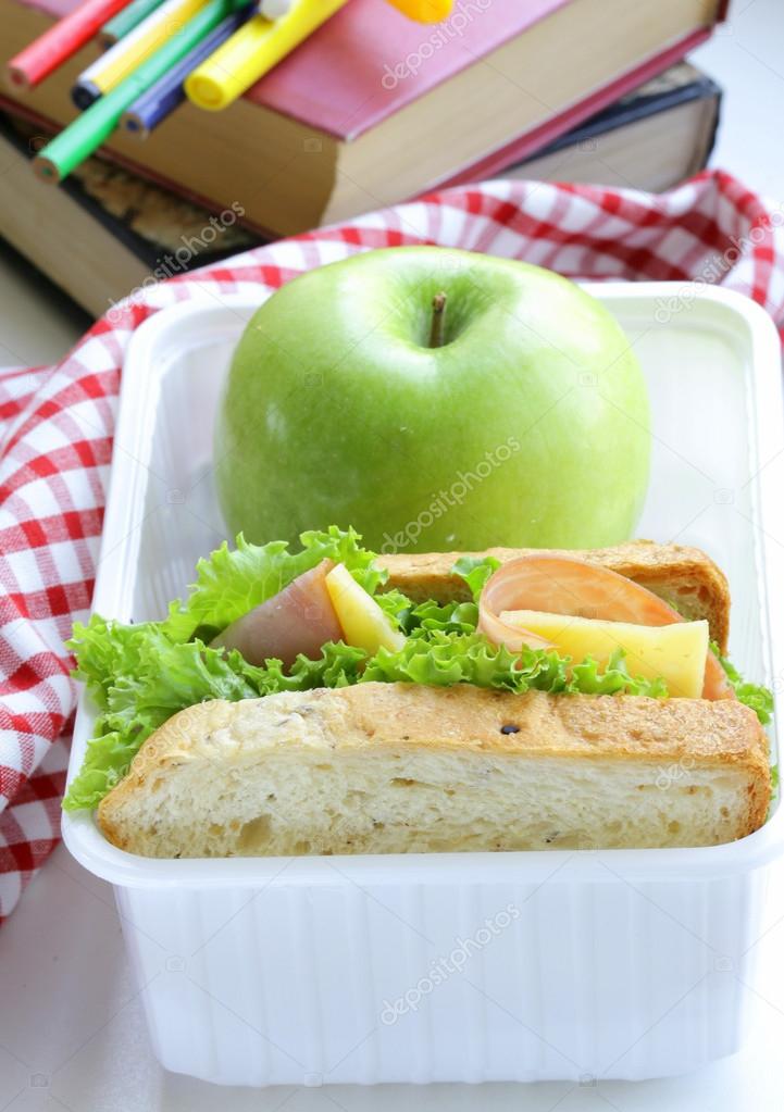Sandwich with ham, green salad and apple in a box - school lunch