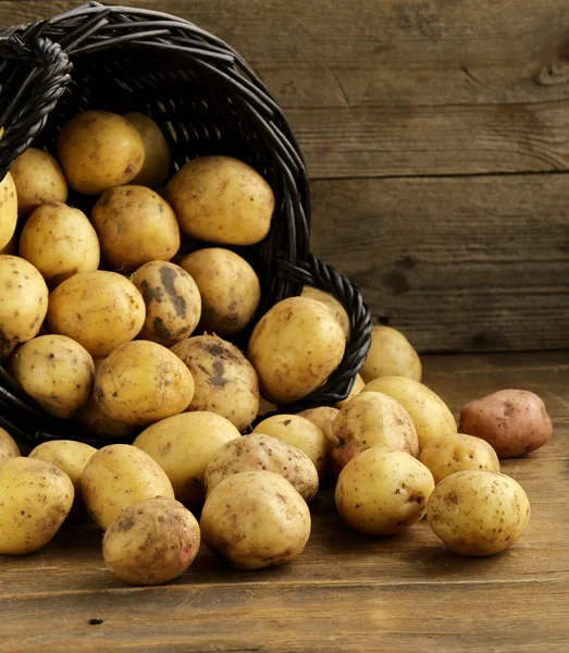 Batatas orgânicas frescas em um fundo de madeira, estilo rústico — Fotografia de Stock