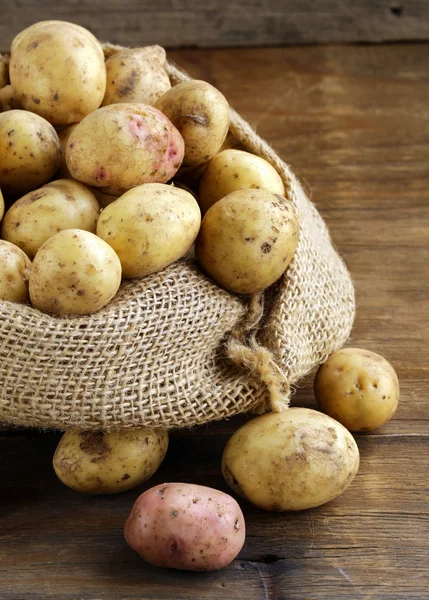 Batatas orgânicas frescas em um fundo de madeira, estilo rústico — Fotografia de Stock