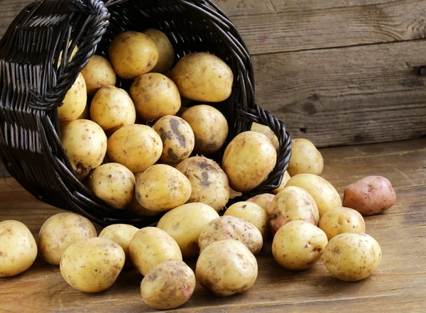 Batatas orgânicas frescas em um fundo de madeira, estilo rústico — Fotografia de Stock