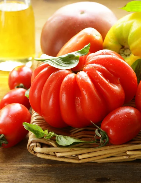 Verschiedene Tomatensorten mit Basilikum auf einem Holztisch — Stockfoto