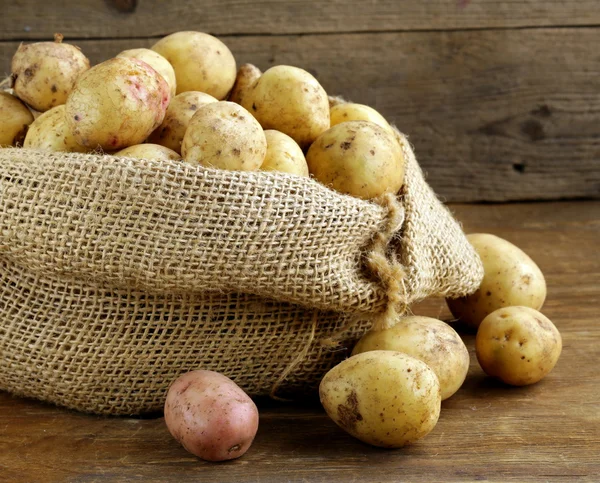 Čerstvé bio brambory na dřevěné pozadí, rustikální styl — Stock fotografie