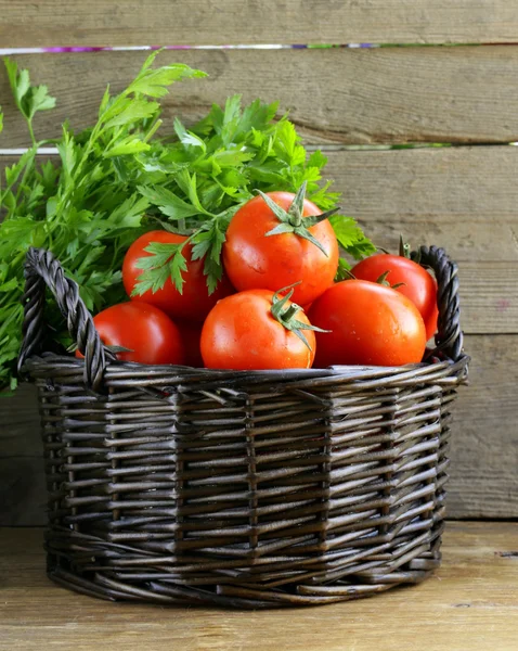 Verse rijpe tomaten in een mand op tafel — Stockfoto