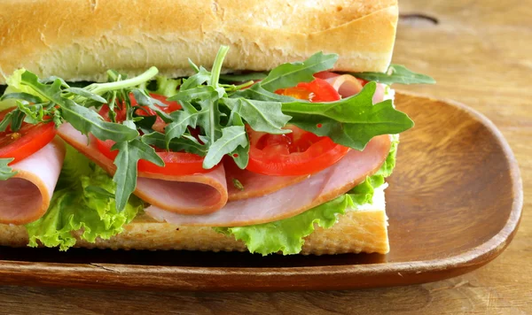 Baguette sandwich with arugula, ham and tomatoes — Stock Photo, Image