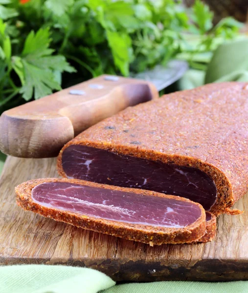 Carne curada - basturma em pimentão quente (páprica) em uma tábua de corte — Fotografia de Stock