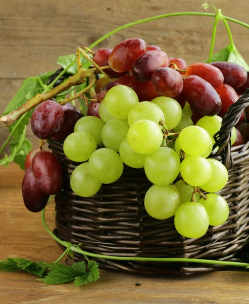 Uvas orgânicas em uma cesta na mesa de madeira — Fotografia de Stock