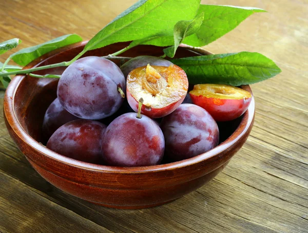 Ciruelas moradas maduras sobre una mesa de madera —  Fotos de Stock