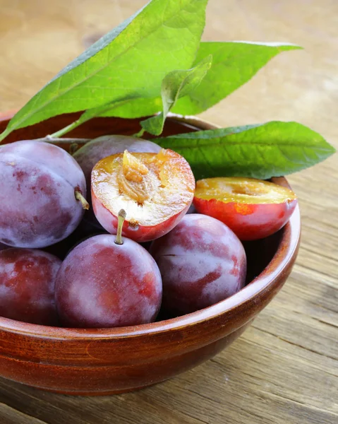 Ciruelas moradas maduras sobre una mesa de madera — Foto de Stock