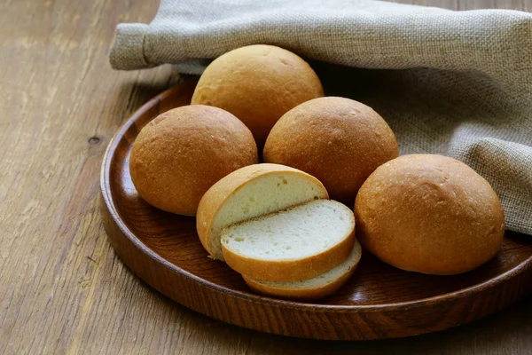 Булочки на дерев'яній тарілці, домашній хліб — стокове фото