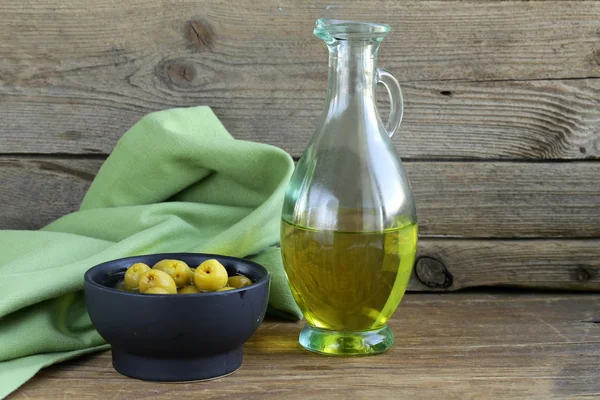 Мариновані зелені оливки і пляшка олії на дерев'яному столі — стокове фото