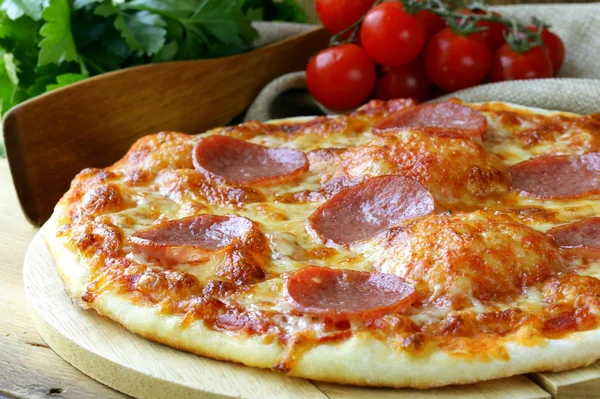 Pizza de pepperoni com molho de tomate em tábua de madeira — Fotografia de Stock