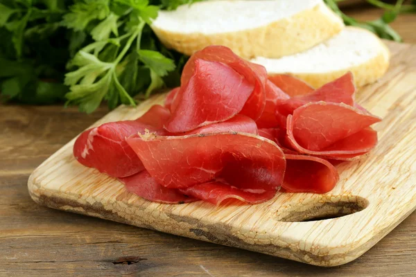 Bresaola di carne affumicata su un tagliere — Foto Stock