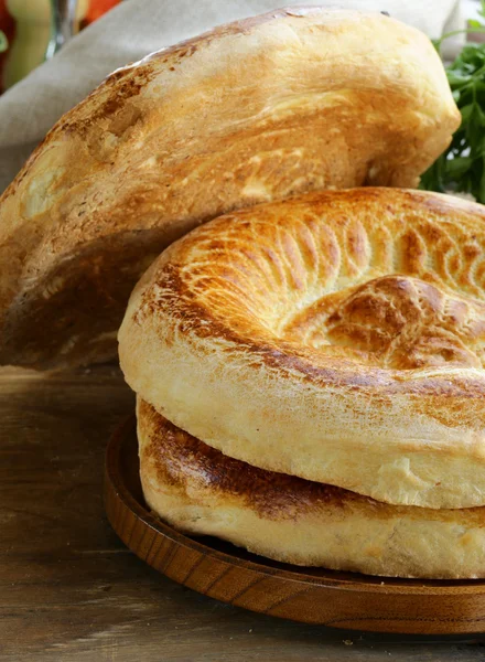 Geleneksel Orta Asya ekmek, ekmeği ahşap bir masa üzerinde kazık. — Stok fotoğraf