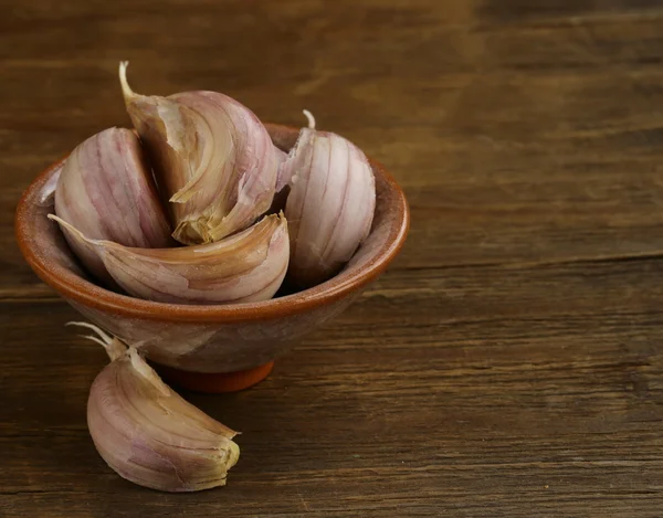 Garlic in bowl on a wooden background — Stock Photo, Image