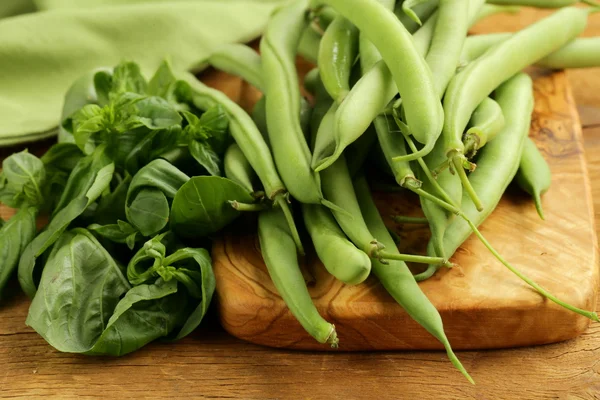 Verse groene bonen en basilicum op het bord van de keuken — Stockfoto