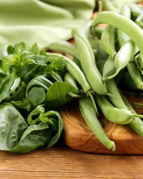 Verse groene bonen en basilicum op het bord van de keuken — Stockfoto