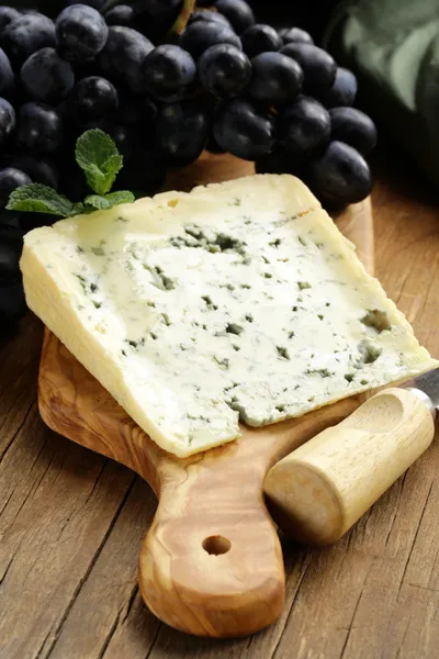 Piece of blue cheese with grapes on a wooden board — Stock Photo, Image