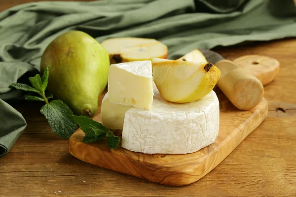 Queso brie suave (camembert) con peras en una tabla de madera —  Fotos de Stock