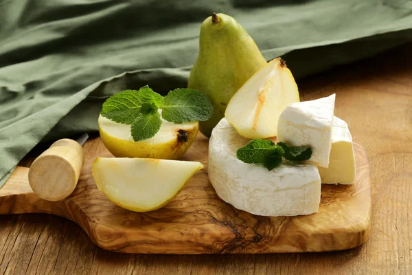 Queso brie suave (camembert) con peras en una tabla de madera —  Fotos de Stock