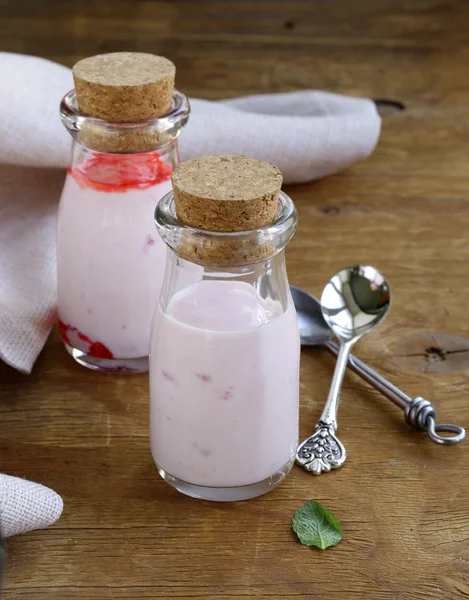 Strawberry yoghurt i glasburkar på ett träbord — Stockfoto