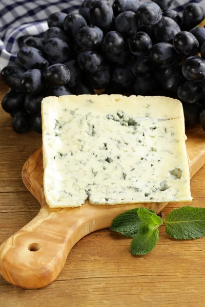 Piece of blue cheese with grapes on a wooden board — Stock Photo, Image