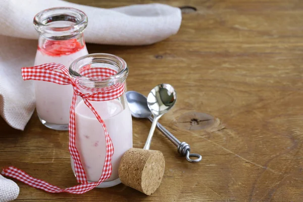 Jogurt truskawkowy w słoikach na drewnianym stołem — Zdjęcie stockowe