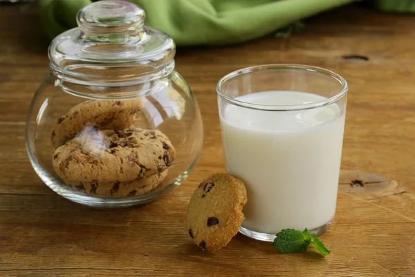 Ontbijt cookies met chocolade en melk op een houten tafel — Stockfoto