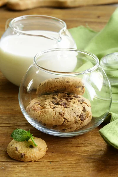 Breakfast cookies with chocolate and milk on a wooden table — Stock Photo, Image