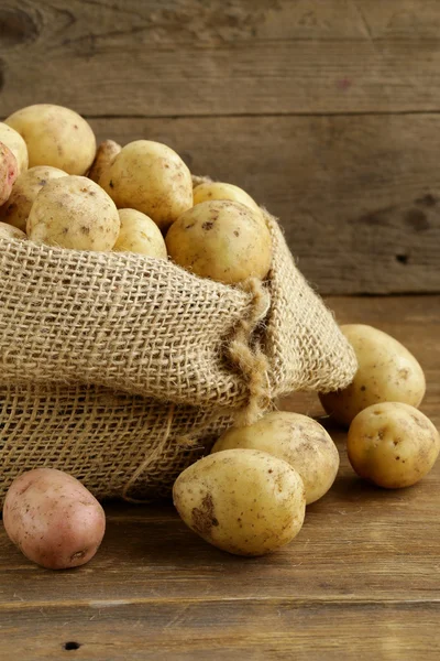 Čerstvé bio brambory na dřevěné pozadí, rustikální styl — Stock fotografie