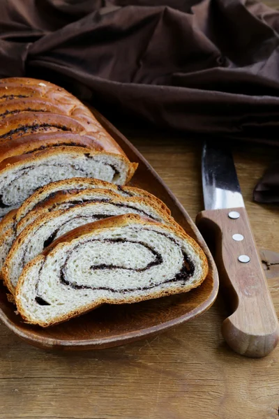 Rouleau de biscuits aux graines de pavot sur une assiette en bois — Photo