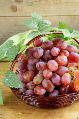 ahşap bir masa üzerinde bir sepet içinde kırmızı olgun organik üzüm