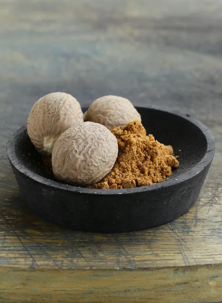 Nutmeg whole and grated in a wooden bowl — Stock Photo, Image