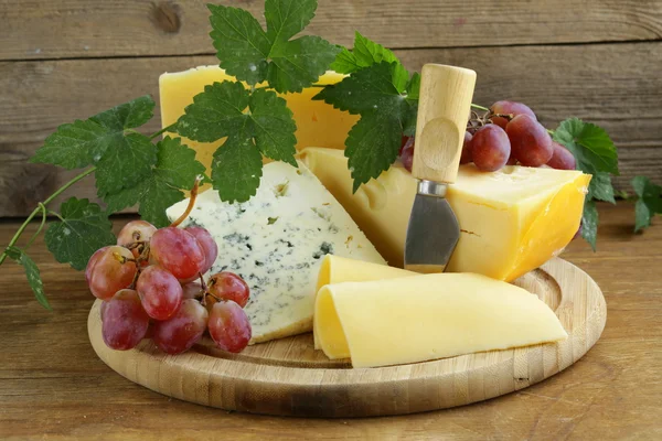 Cheeseboard (Maasdam, Roquefort, Camembert) and grapes for dessert — Stock Photo, Image