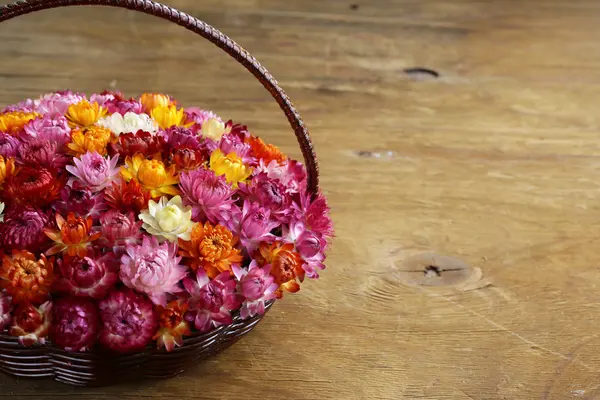 Cesta de mimbre con flores multicolores sobre mesa de madera — Foto de Stock