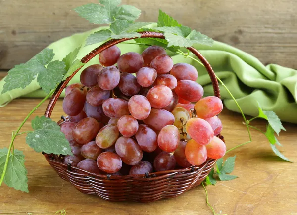 Спелый красный органический виноград в корзине на деревянном столе — стоковое фото