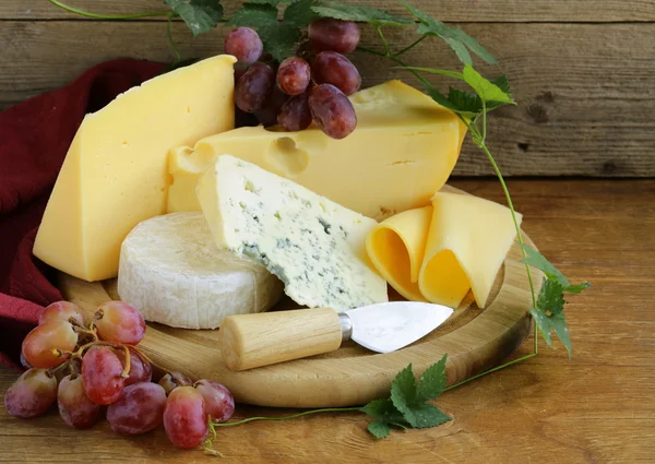 Cheeseboard (maasdam, roquefort, camembert) och druvor till efterrätt — Stockfoto