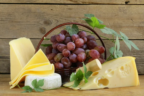 Cheeseboard (Maasdam, Roquefort, Camembert) and grapes for dessert — Stock Photo, Image