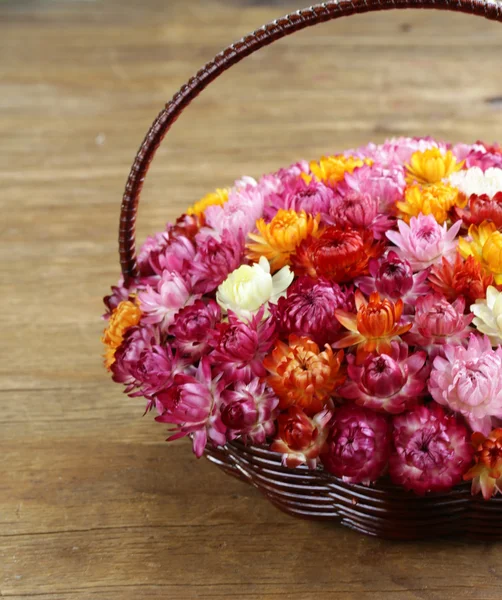 Cesta de mimbre con flores multicolores sobre mesa de madera —  Fotos de Stock