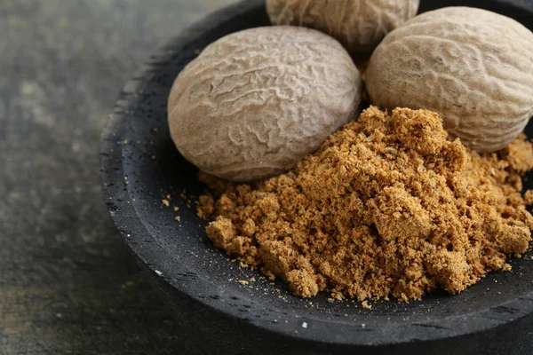 Nutmeg whole and grated in a wooden bowl — Stock Photo, Image